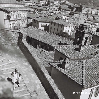 Aerial view of a cityscape with buildings and a person walking on a rooftop.