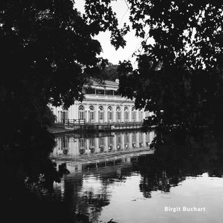 Black and white photograph of a building reflected in water with trees framing the scene.