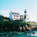 Lighthouse and coastal buildings with boats in the foreground