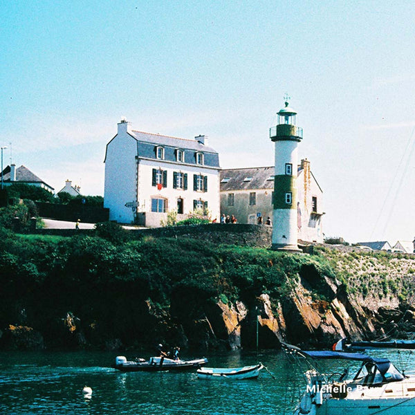 Lighthouse and coastal buildings with boats in the foreground