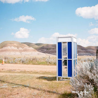 Phone booth in a desert landscape with mountains in the background
