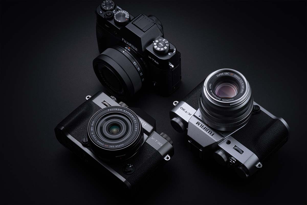 Three black Fujifilm cameras on a dark background