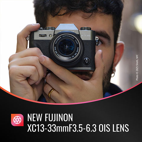 Person holding a camera with a Fujifilm lens, featuring the new Fujinon XC13-33mmF3.5-6.3 OIS lens.