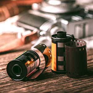 Vintage film reels and a camera part on a wooden surface, possibly indicating a film processing service.