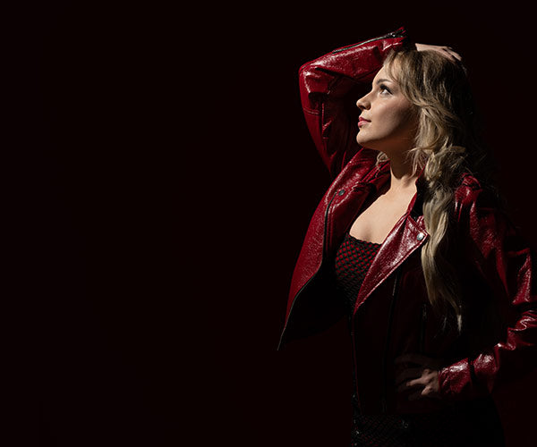 Woman wearing a red leather jacket against a dark background