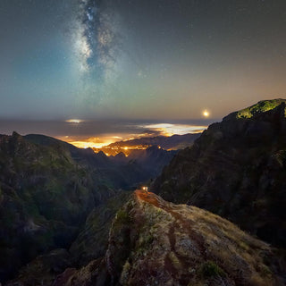 sunset mountains with hiker in the distance holding a lantern
