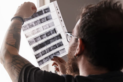 man holding 35mm film negatives up to study