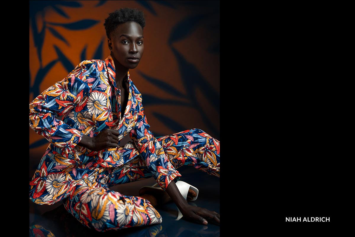 Person wearing a colorful floral suit against a dark background