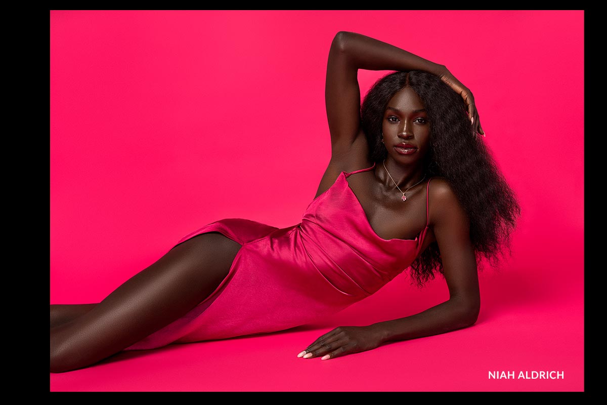 Woman in a pink dress lying on a pink background with 'Niah Aldrich' branding.