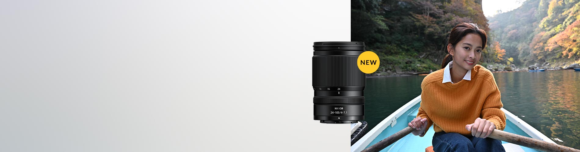 Person in an orange sweater rowing a boat with a camera lens labeled 'NEW' in the foreground.