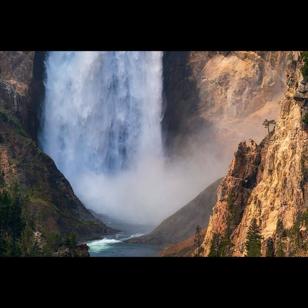 A dramatic landscape photograph of a large waterfall cascading down steep rocky cliffs into a river below, with mist rising and trees along the canyon edges.