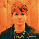 Person with styled hair and chains in front of a wooden background, with 'Michelle Parr' text.