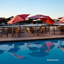 Outdoor dining area with red umbrellas and tables by a pool, featuring the photographer's name 'Birgit Buchart'.