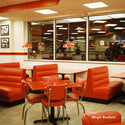Diner interior with red booths and tables, featuring a large window.