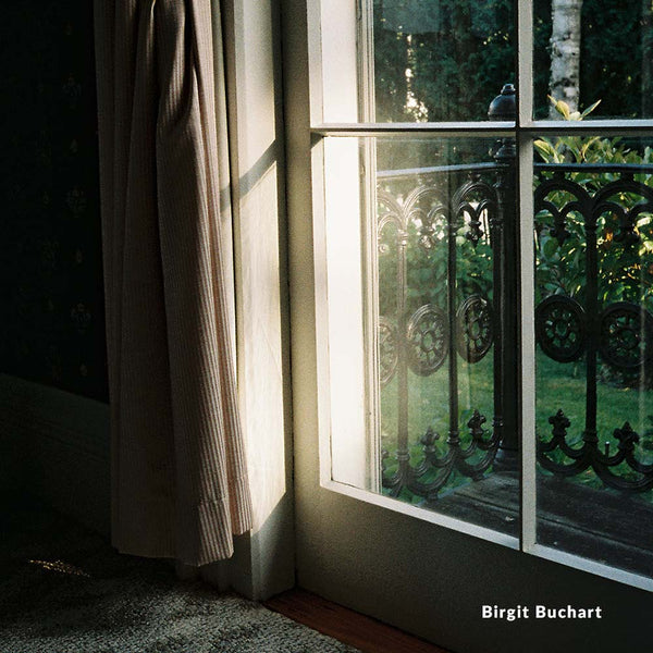 Window with decorative iron grille and light filtering through, with 'Birgit Buchart' credit.