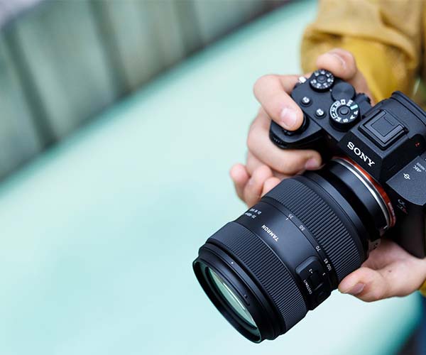 Sony camera with lens held in a hand against a blurred background